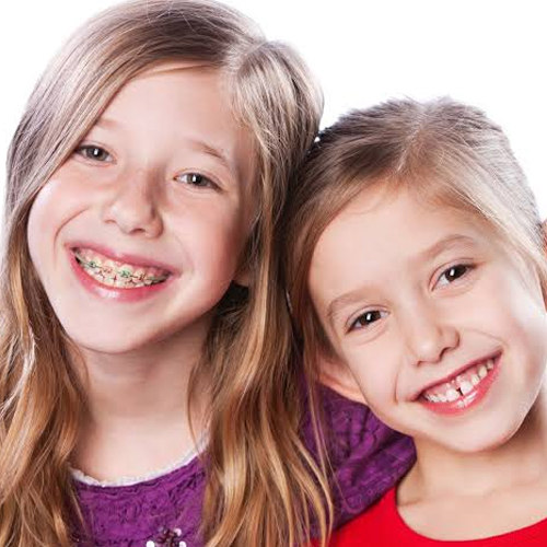 Beugel kind welke leeftijd Hoogvliet - Orthodontie Hoogvliet Twee jonge, lachende meisjes waarvan één een beugel draagt, ter illustratie van kindvriendelijke orthodontie bij Orthodontie Hoogvliet.